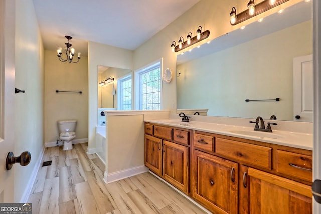 bathroom with vanity, an inviting chandelier, hardwood / wood-style floors, toilet, and a tub