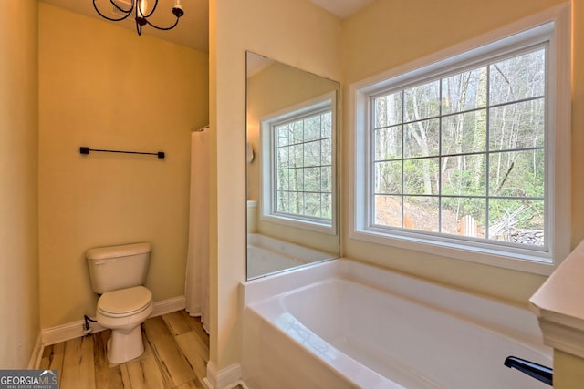 bathroom with hardwood / wood-style flooring, toilet, a tub, and a wealth of natural light