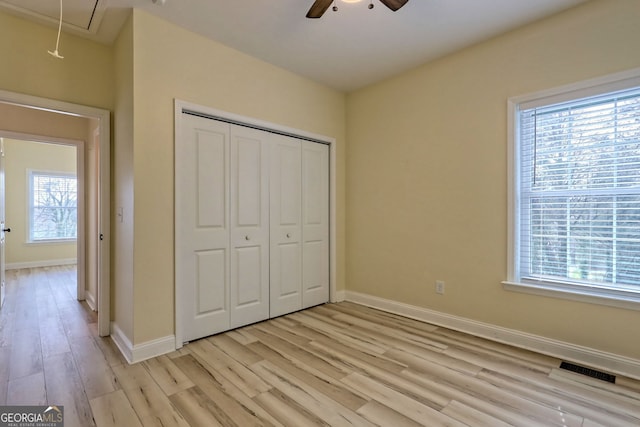 unfurnished bedroom featuring a closet, multiple windows, ceiling fan, and light hardwood / wood-style flooring