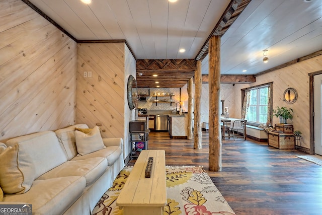 living room featuring dark hardwood / wood-style floors, wooden walls, and sink