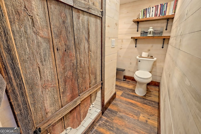 bathroom featuring hardwood / wood-style flooring, toilet, and wooden walls