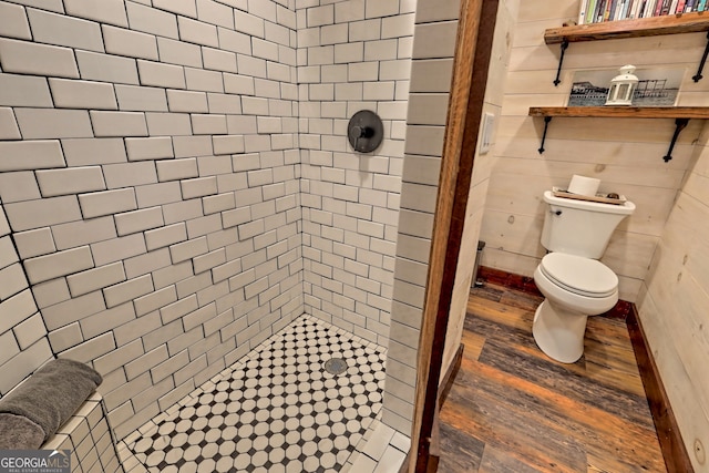 bathroom with a tile shower, wood-type flooring, and toilet