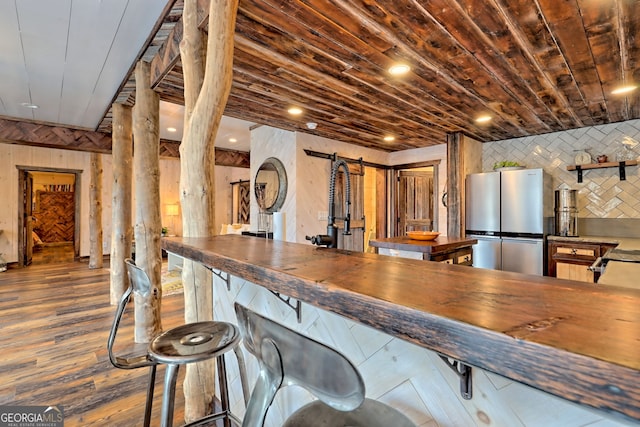 bar featuring stainless steel fridge, butcher block counters, and backsplash