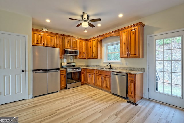 kitchen with light wood-type flooring, stainless steel appliances, a wealth of natural light, and sink