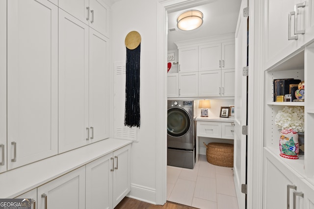 laundry room with light tile patterned flooring, cabinets, and washer / dryer