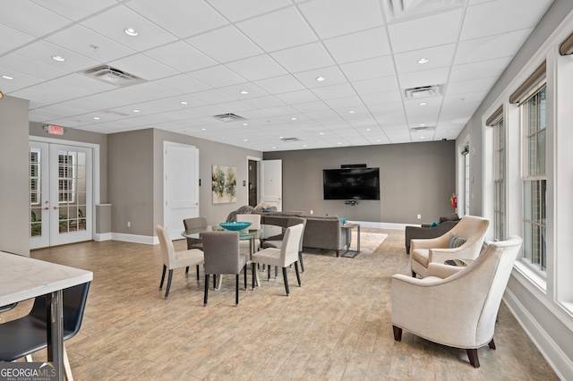 dining area featuring a paneled ceiling, light hardwood / wood-style floors, and french doors