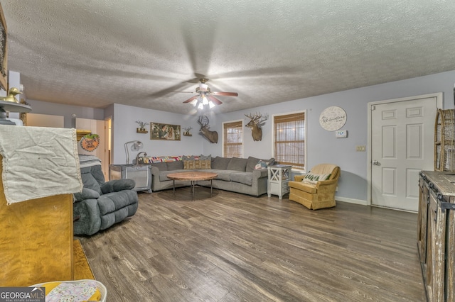 living area featuring a textured ceiling, dark wood-type flooring, a ceiling fan, and baseboards