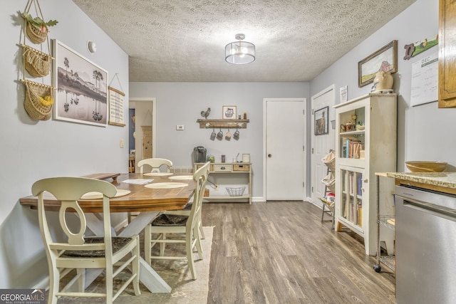 dining space with a textured ceiling and wood finished floors