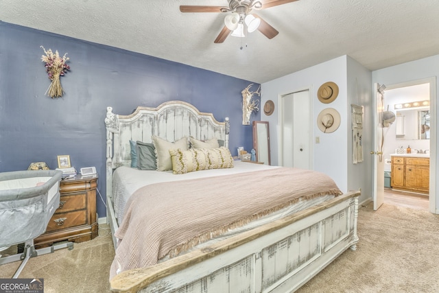 bedroom with a textured ceiling, a ceiling fan, a closet, carpet, and ensuite bath