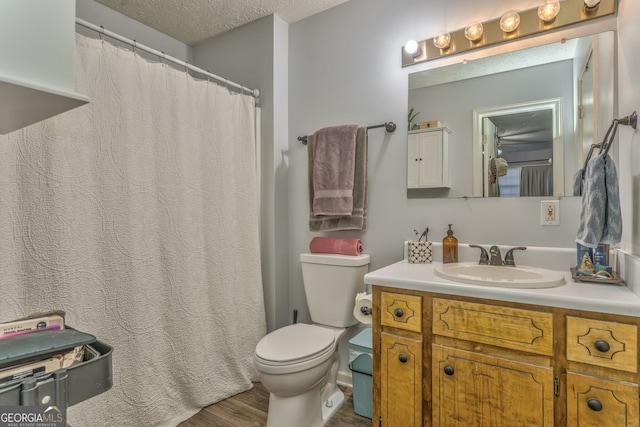 full bathroom featuring toilet, wood finished floors, a textured ceiling, and vanity