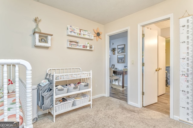 bedroom featuring light carpet, baseboards, and a textured ceiling