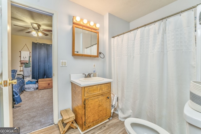 full bath with a ceiling fan, toilet, wood finished floors, a textured ceiling, and vanity