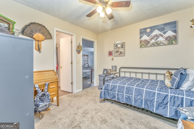 bedroom featuring baseboards, connected bathroom, a ceiling fan, light colored carpet, and a textured ceiling