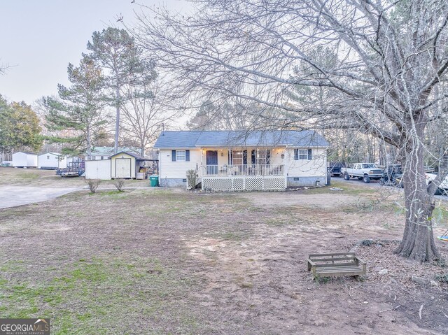 ranch-style home featuring covered porch and a storage unit