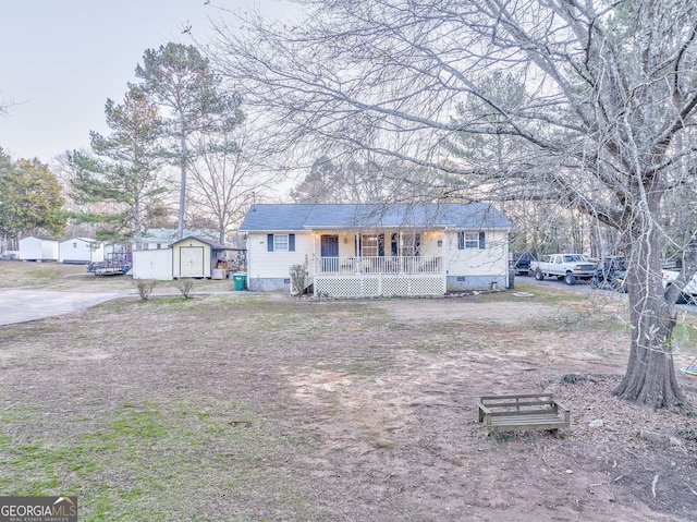 view of front of house with driveway, an outbuilding, crawl space, a storage unit, and a porch