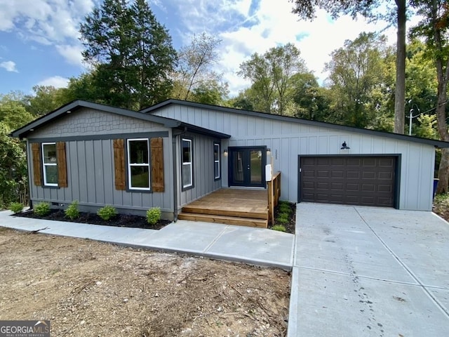 view of front facade featuring a garage, a wooden deck, and french doors