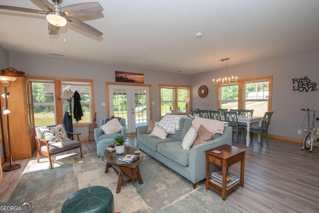 living room featuring french doors, ceiling fan with notable chandelier, plenty of natural light, and hardwood / wood-style flooring