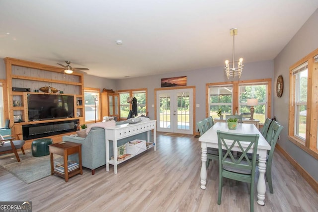 dining space featuring ceiling fan with notable chandelier, light wood-type flooring, and french doors