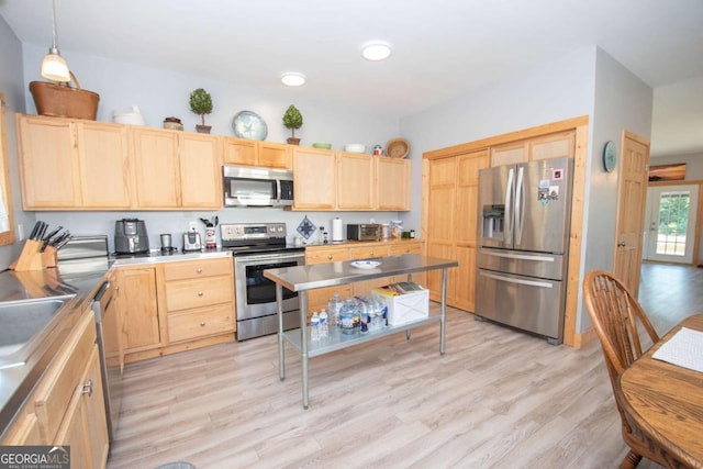 kitchen featuring light wood-type flooring, decorative light fixtures, light brown cabinets, and stainless steel appliances