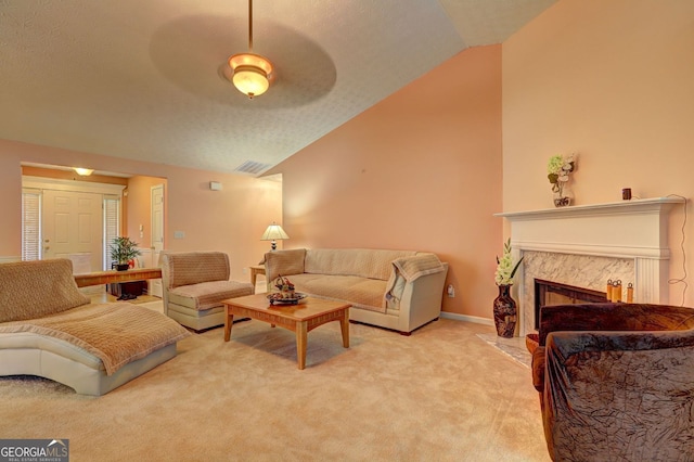 living room with ceiling fan, light colored carpet, a fireplace, and vaulted ceiling