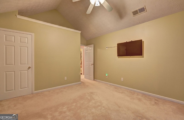 unfurnished bedroom with a textured ceiling, light colored carpet, vaulted ceiling, and ceiling fan