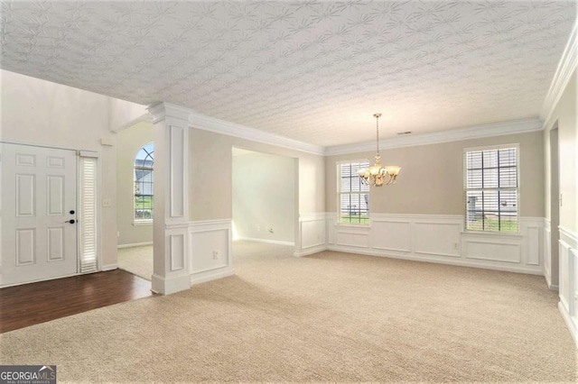 interior space with carpet flooring, a chandelier, plenty of natural light, and ornamental molding