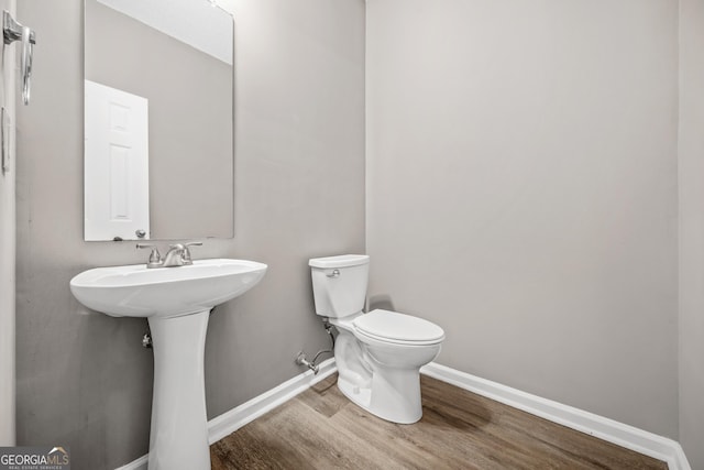 bathroom with wood-type flooring, toilet, and sink