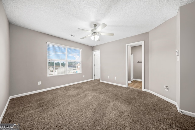 unfurnished bedroom featuring carpet flooring, a textured ceiling, a closet, and ceiling fan