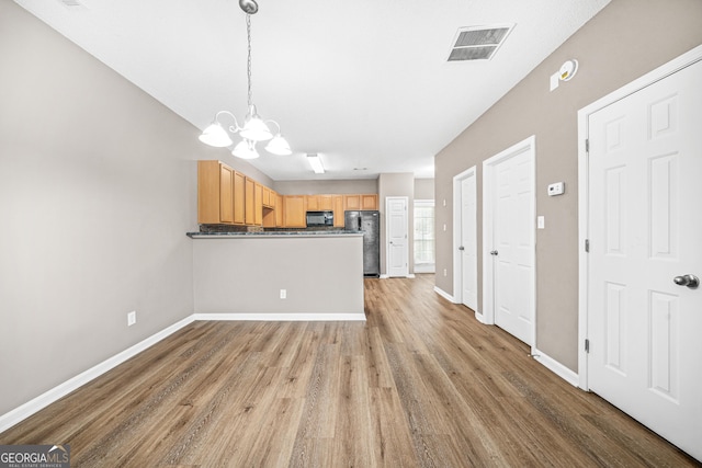 kitchen with black appliances, wood-type flooring, light brown cabinets, decorative light fixtures, and an inviting chandelier