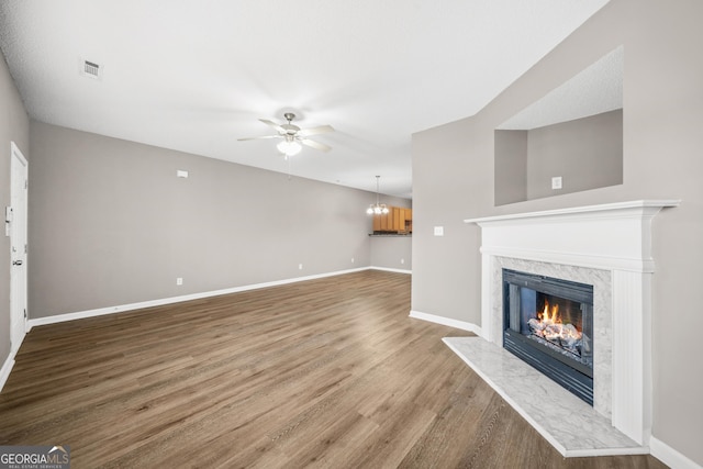 unfurnished living room with a fireplace, hardwood / wood-style floors, and ceiling fan with notable chandelier