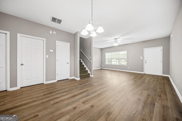 unfurnished living room featuring ceiling fan with notable chandelier and dark hardwood / wood-style floors