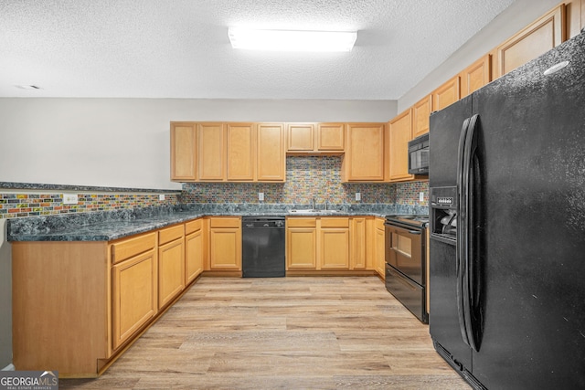 kitchen with light brown cabinets, black appliances, light hardwood / wood-style flooring, dark stone countertops, and a textured ceiling