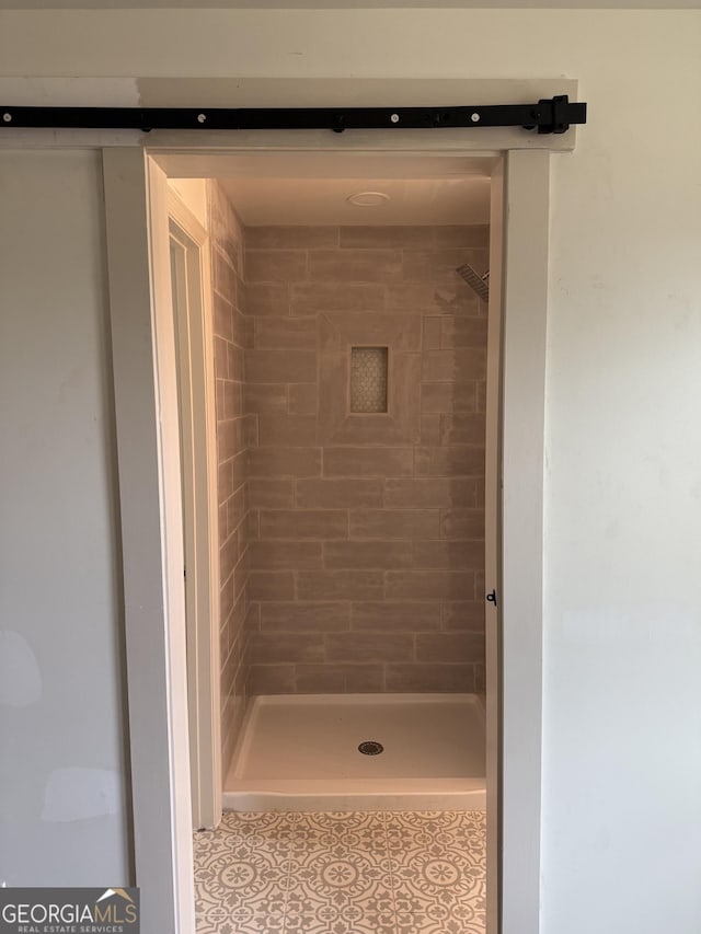 bathroom featuring tiled shower and tile patterned flooring