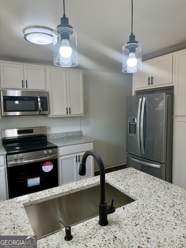 kitchen featuring pendant lighting, sink, white cabinets, backsplash, and stainless steel appliances