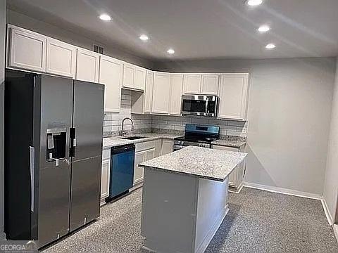 kitchen with white cabinetry, sink, black appliances, and a kitchen island