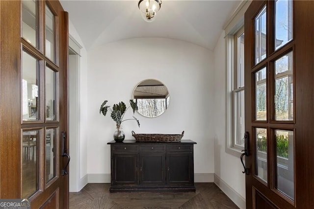 foyer entrance featuring dark parquet flooring and lofted ceiling