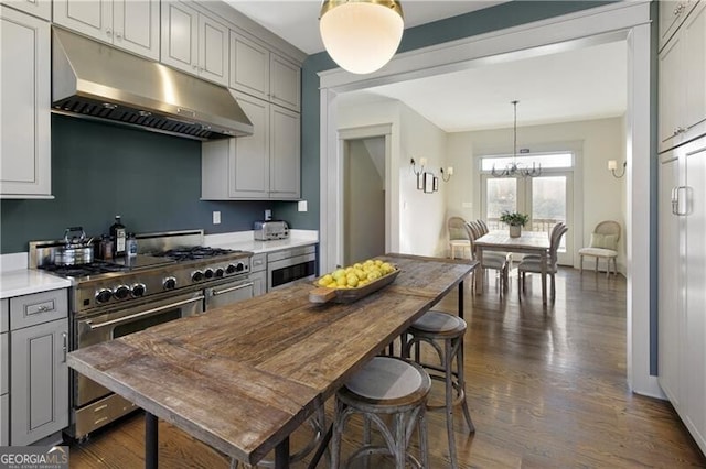 kitchen featuring stainless steel range, pendant lighting, gray cabinetry, and a notable chandelier