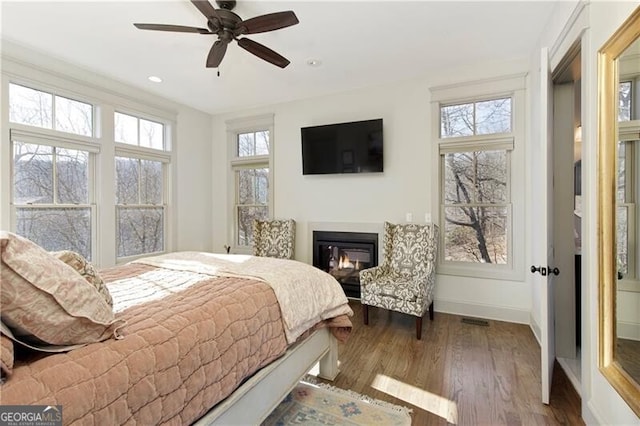 bedroom featuring hardwood / wood-style floors, ceiling fan, and multiple windows
