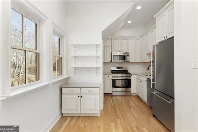 kitchen featuring light wood-type flooring, white cabinetry, appliances with stainless steel finishes, and tasteful backsplash