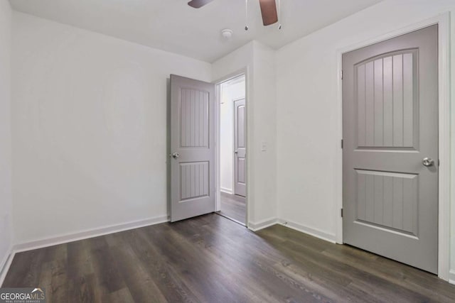 unfurnished bedroom with ceiling fan and dark wood-type flooring