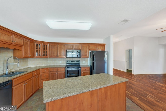 kitchen with appliances with stainless steel finishes, backsplash, light stone counters, and sink