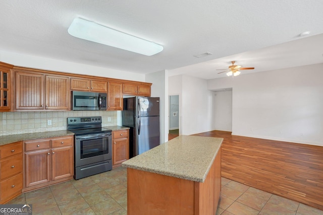 kitchen with a center island, black fridge, electric stove, decorative backsplash, and light tile patterned flooring