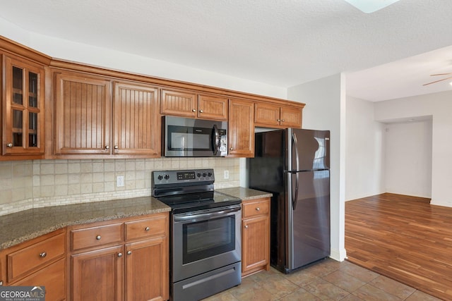 kitchen featuring appliances with stainless steel finishes, backsplash, ceiling fan, light tile patterned floors, and dark stone countertops