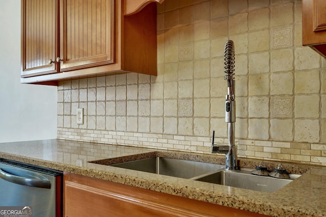 kitchen with dishwasher, sink, light stone counters, and backsplash