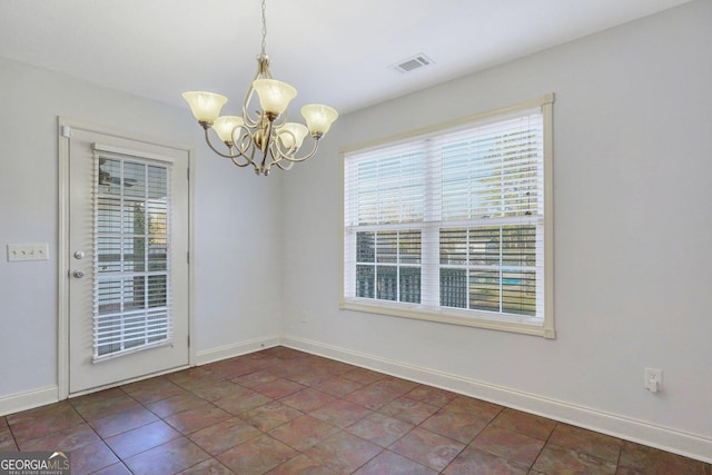 spare room with dark tile patterned flooring and an inviting chandelier