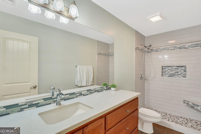 bathroom with vanity, backsplash, tile patterned floors, toilet, and tiled shower