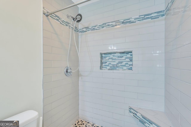 bathroom with toilet and a tile shower