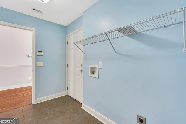 clothes washing area featuring hookup for a washing machine, dark tile patterned flooring, and electric dryer hookup