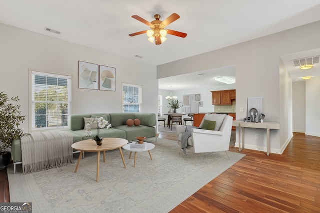 living room featuring ceiling fan with notable chandelier and hardwood / wood-style flooring