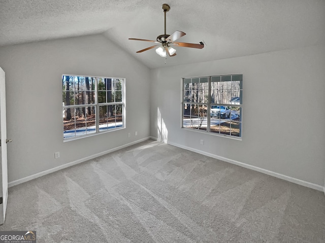 empty room with carpet flooring, a textured ceiling, vaulted ceiling, and ceiling fan